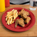 A red Carlisle Sierrus melamine plate with fried chicken and french fries.
