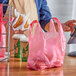 A man using a pink plastic Choice medium-duty T-shirt bag to carry food.
