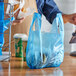 A person holding a blue plastic bag with food in it.