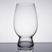 A close-up of a clear Spiegelau American wheat beer glass on a table.