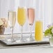 A Libbey tall flute glass filled with yellow champagne on a tray with flowers.