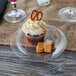A cupcake with a pretzel and caramel on a Visions clear plastic plate.