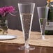 Two Visions clear plastic champagne flutes on a table with flowers.