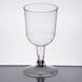 A Visions clear plastic wine goblet with a long stem and base on a table.