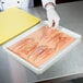 A person using LitePeachTreat steak paper to hold raw chicken breasts.