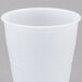 A Dart translucent plastic cup with a white lid on a gray surface.