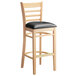A Lancaster Table & Seating wooden bar stool with a black cushion on the seat.