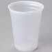 A Dart translucent plastic cup with a clear lid on a gray surface.