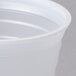 A close-up of a Dart translucent plastic cup with a lid.