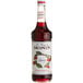 A bottle of Monin cherry syrup with a white label.