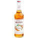A bottle of Monin caramel syrup with a white label.