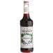 A bottle of Monin Black Currant syrup with a white label.