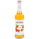 A Monin 750 mL bottle of peach syrup.