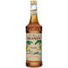 A bottle of Monin Organic Vanilla Flavoring Syrup with a brown label and brown liquid.