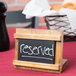 A Cal-Mil Madera chalkboard stand with white text reading "Reserved" on a table.
