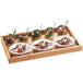 A Madera rustic pine serving tray with four dishes of food on a white surface.