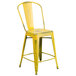 A yellow metal Flash Furniture restaurant bar stool with a vertical slat back and drain hole seat.