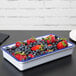 A white rectangular melamine tray with blue trim holding a bowl of strawberries.