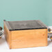 A wooden box with a Cal-Mil Madera butane range frame on top and bowls of food.