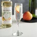 A glass of champagne with Monin White Peach syrup on the table.