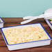Three white Cal-Mil enamelware trays with blue rim on a table with macaroni and cheese.
