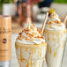 Two milkshakes with Monin caramel flavoring sauce and whipped cream in a glass.