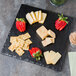 A Cal-Mil faux slate melamine serving platter with cheese and strawberries on it.
