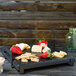 A Cal-Mil faux slate melamine serving platter with cheese and strawberries on it.