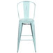 A blue metal bar stool with a vertical slat back and a drain hole seat.