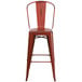 A red metal bar stool with a backrest.