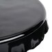 A black melamine cake stand with a ruffled edge on a table.
