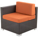 A BFM Seating Aruba outdoor wicker end armchair with orange cushions.
