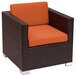 A brown wicker armchair with orange cushions.