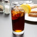 A Libbey customizable cooler glass of iced tea with a lemon wedge.