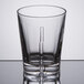 A clear Spiegelau whiskey glass with a metal rim on a table.