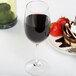 A Spiegelau Vino Grande port wine glass filled with red wine next to a dessert with strawberries.