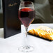 A Spiegelau Adina Prestige red wine glass filled with wine next to a plate of cheese and crackers.