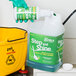 A gloved hand pours green Step and Shine floor cleaner into a Noble Chemical container.