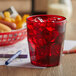 A red GET Bahama plastic tumbler filled with ice and a red drink on a table with a red basket of food.