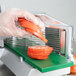 A person in gloves using a Garde tomato slicer to slice carrots.