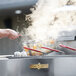A person using a Crown Verity double tank outdoor fryer to cook food on a counter.