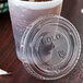 A plastic cup with a Solo clear plastic lid and a straw slot on a table.