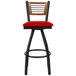 A BFM Seating black metal bar stool with a cherry wood back and red vinyl swivel seat.