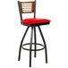 A black metal restaurant bar stool with a cherry wood back and red vinyl swivel seat.
