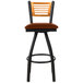 A BFM Seating black metal restaurant bar stool with a light brown vinyl swivel seat and natural wooden back.