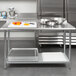 A Steelton stainless steel work table with an undershelf holding food.