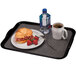 A black Cambro rectangular tray with a croissant sandwich, strawberries, and a cup of coffee.