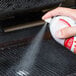 Grid Iron Sprease spray being used on a grill.