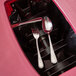 A spoon and fork in a San Jamar KatchAll flatware retriever lid.