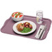 A purple Cambro rectangular tray with food on it on a table with a glass of water.